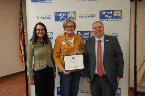 Two award recipients hold a certificate with the board chair