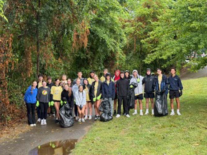 Student volunteers with trash bags along a wooded park path