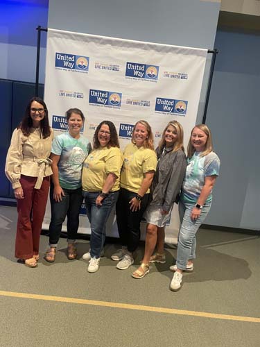 Six volunteers posing together at the United Way banner