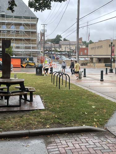 Volunteers picking up litter along a downtown street in the rain
