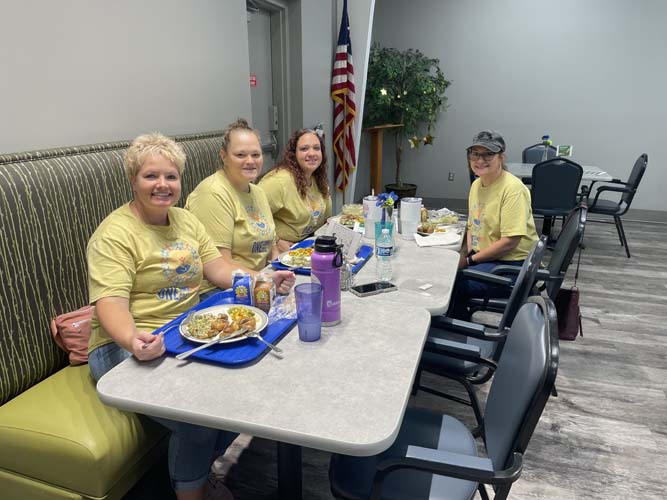 Four volunteers sharing lunch together at a table indoors