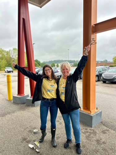 Two volunteers cheering with their arms raised at a project site