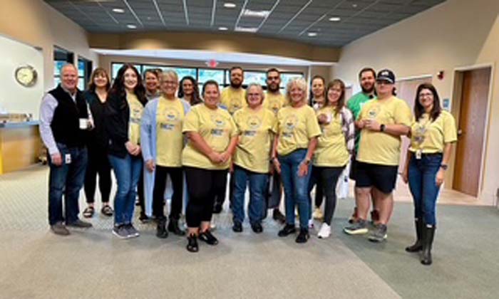 A large group of volunteers gathered in a building lobby for a team photo