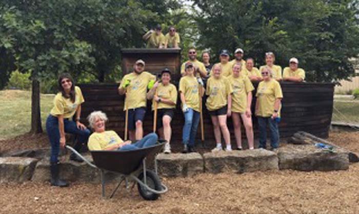 A group of volunteers posing with a wheelbarrow at a completed playground project