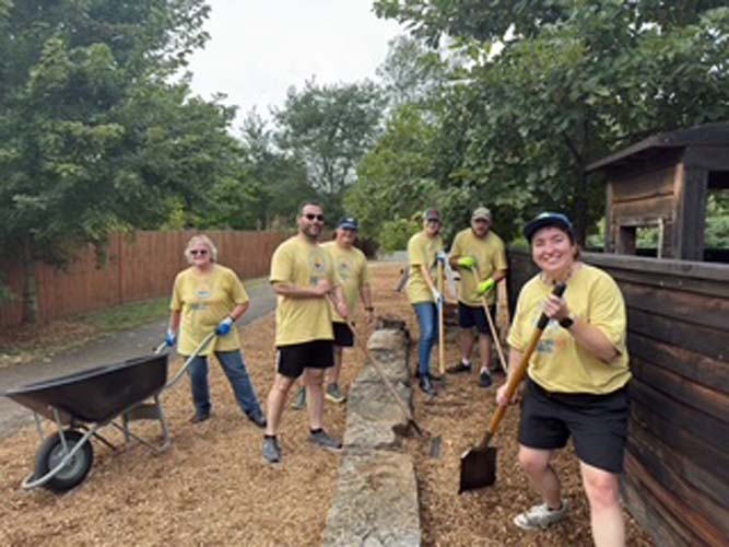 A crew spreading mulch along a playground path