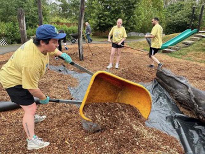 A volunteer shoveling mulch at a playground