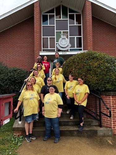 A team of volunteers posing on the front steps of a church