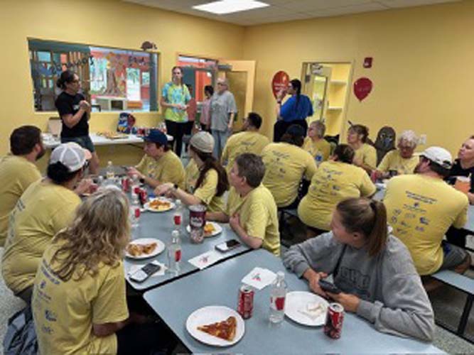 Volunteers sharing a pizza lunch in a school cafeteria