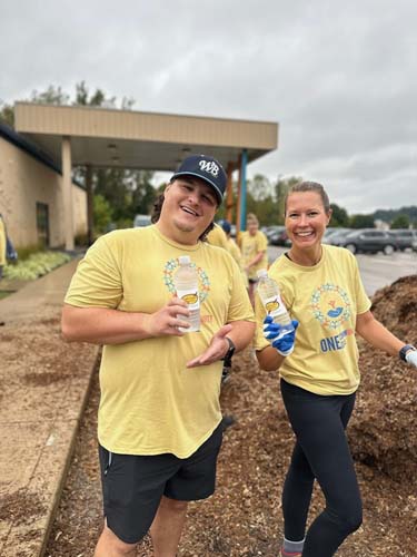 Two volunteers taking a water break beside a mulch pile