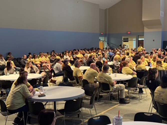 A hall full of volunteers seated at round tables for the kick-off