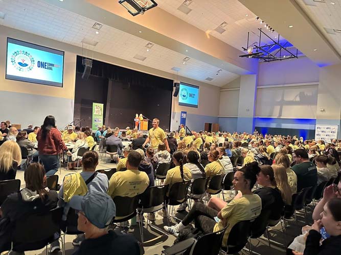 The kick-off crowd facing the stage with One Community One Goal on screen
