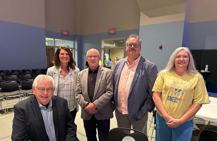 Five community leaders posing in a meeting room