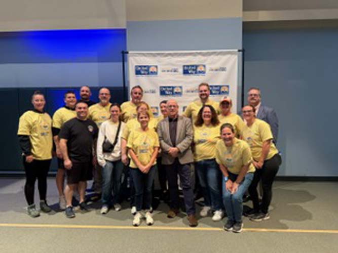 A large group of volunteers posing with staff at the United Way banner