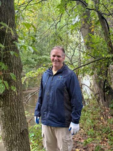 A volunteer standing beside the creek at a stream cleanup site