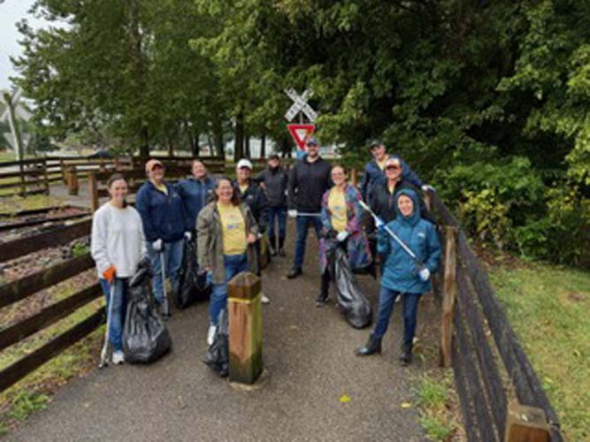 A group of volunteers with trash bags and grabbers on a rail-trail path