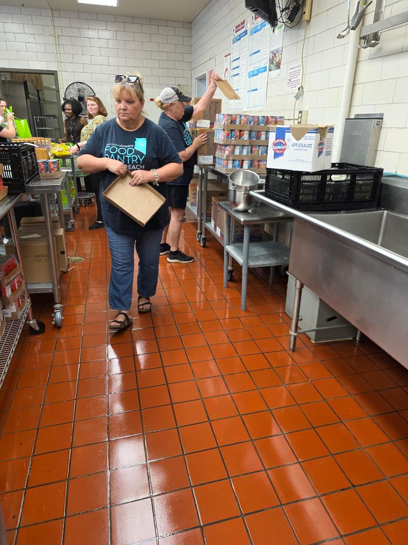 Lancaster Vineyard Food Pantry volunteers unpacking cases of canned food in a school kitchen