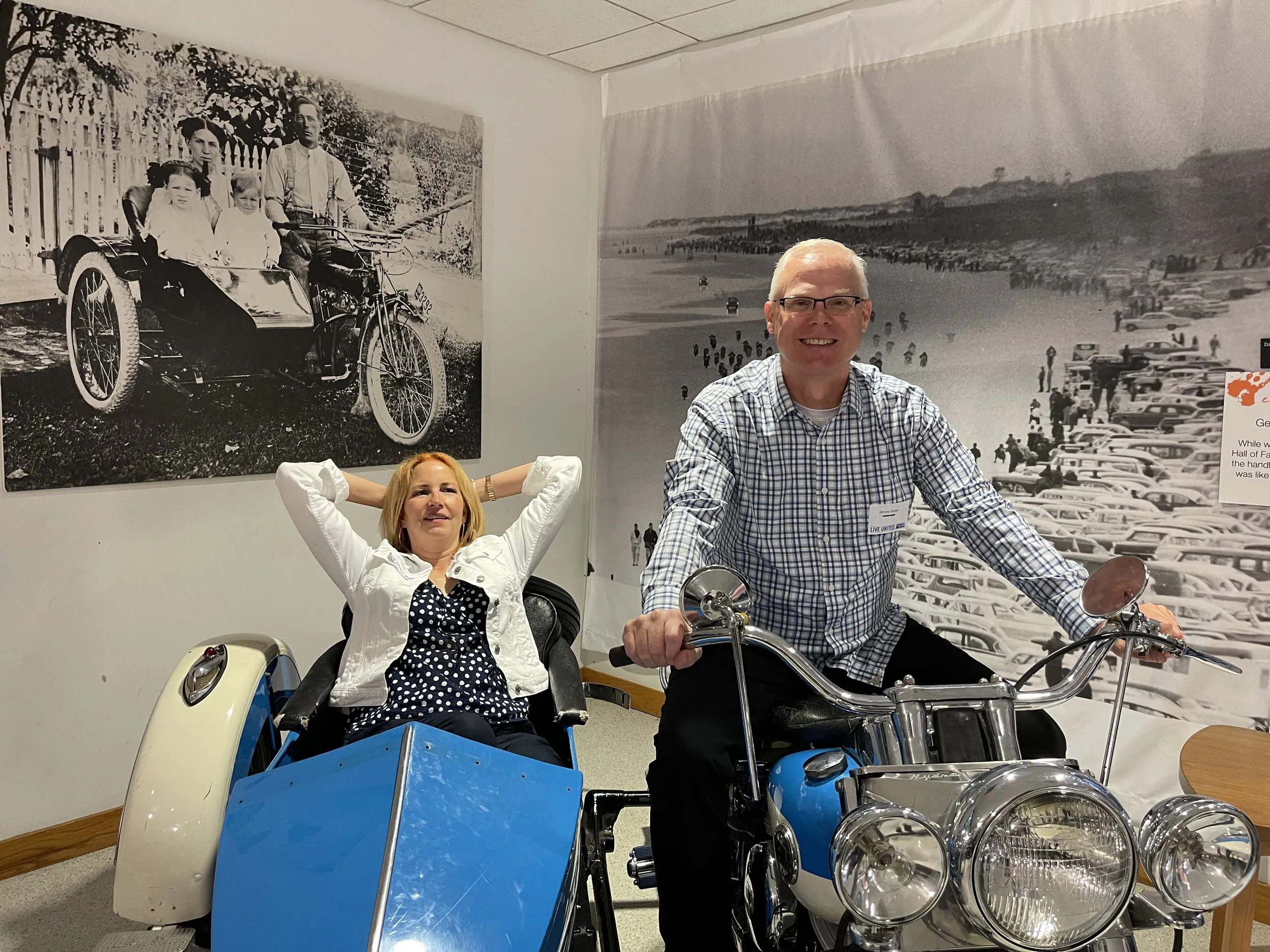 A guest at the handlebars of the vintage motorcycle while another sits in the sidecar