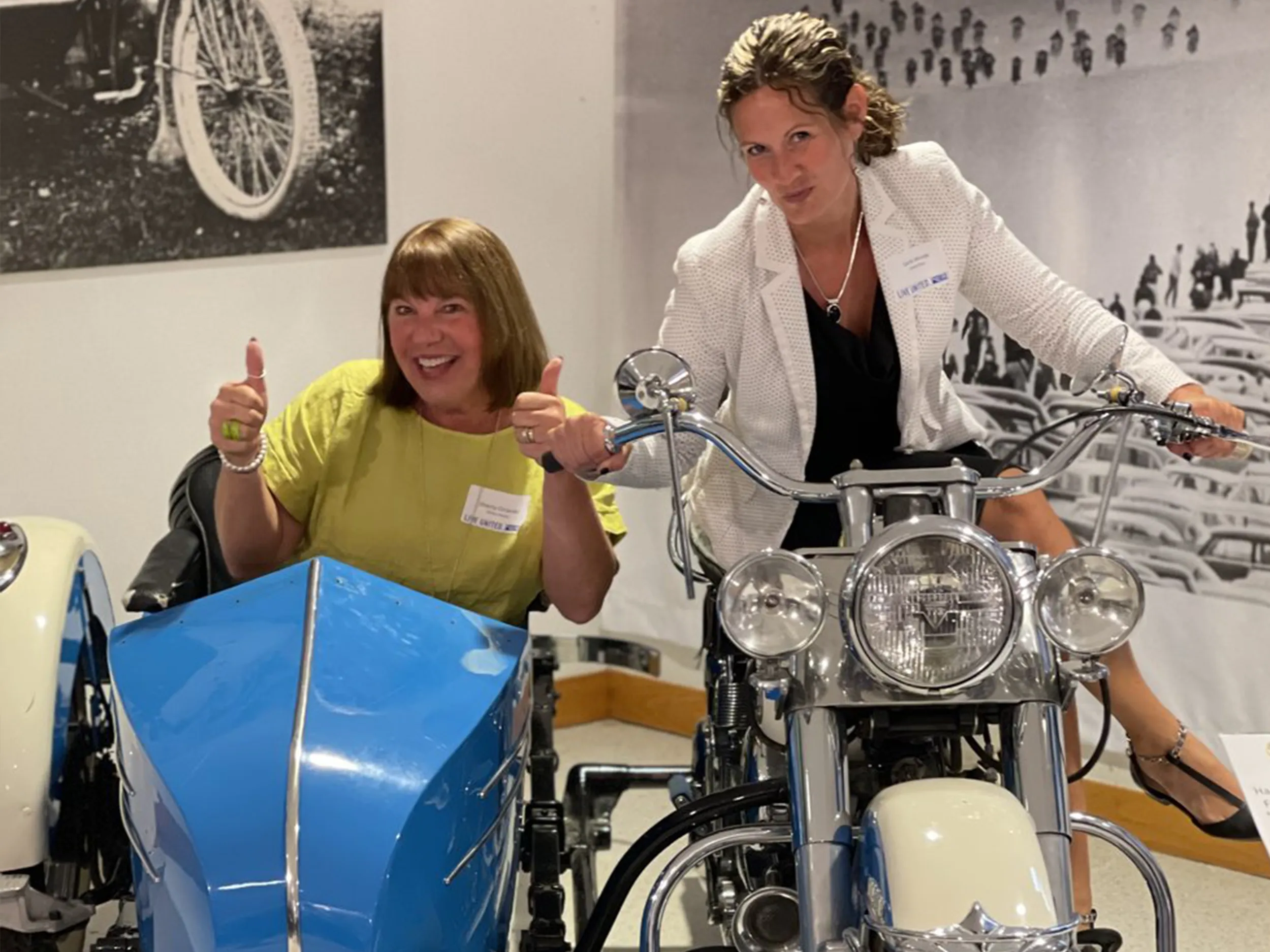 Two attendees posing with the vintage Harley-Davidson